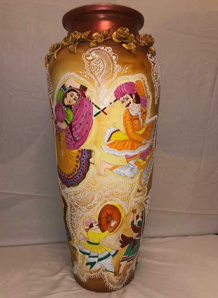 Painting by Anupriya Nagar: Folk dancers with dhol and dandiya, painted and gilded on a tall vase